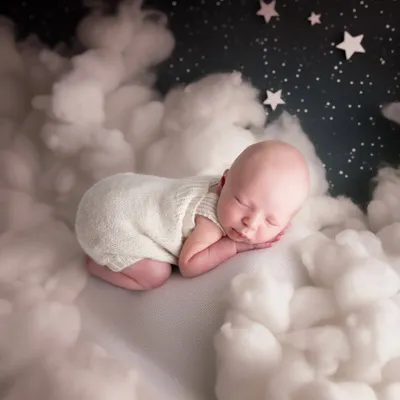 Asleep on a bed of clouds under a starry night sky. This newborn portrait is all about softness and dreams, capturing the pure and peaceful nature of a brand new baby.