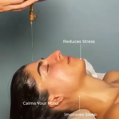 A close-up of a client experiencing Shirodhara. This therapy is incredibly effective at reducing stress, calming the mind, and improving sleep quality by soothing the entire nervous system.