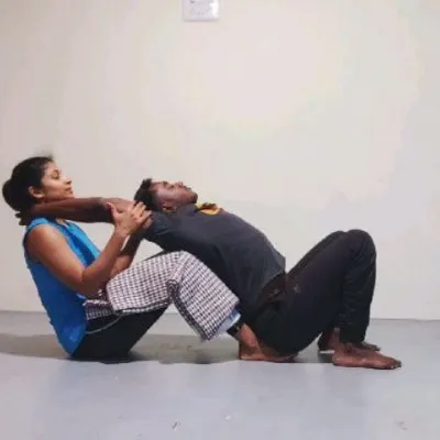 Here, I am assisting a student in a gentle backbend, using my body to provide stable support. This allows her to open her chest and thoracic spine with a sense of security and trust.