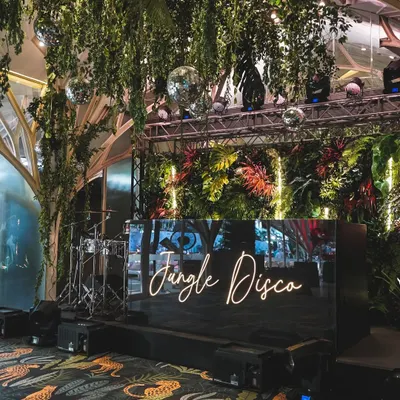 The centerpiece of our "Jungle Disco" theme. We designed a custom DJ booth framed by lush foliage and neon lights, creating an energetic focal point for the evening's celebrations.