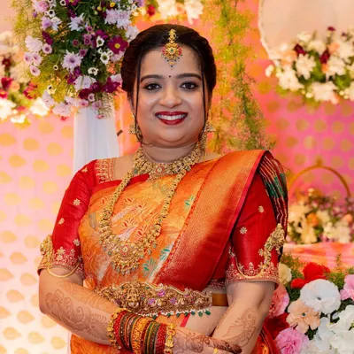 A close-up portrait of Priya for her daughter's naming ceremony. Her makeup is classic and celebratory, with a bright smile and traditional jewelry.