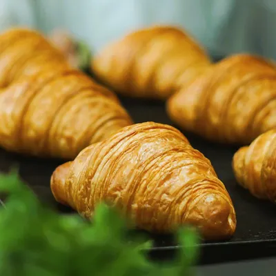 A close-up of our perfectly baked, flaky croissants. These are a Sunday morning essential, best enjoyed warm with butter and jam or our hazel coco spread.