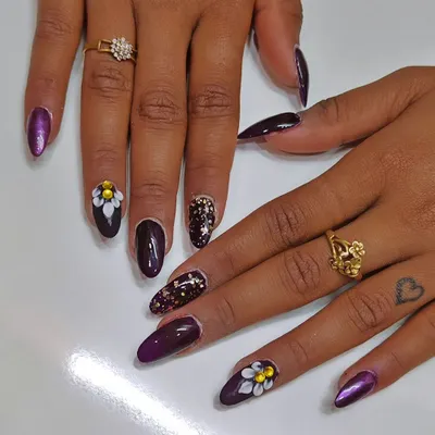 A closer look at the 3D floral nail art. Each petal is sculpted by hand, creating a raised texture that you can see and feel. This is paired with a deep purple polish and a shattered glitter accent nail.