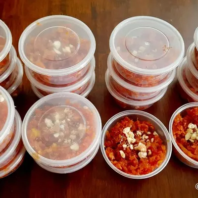 Stacks of my homemade carrot halwa, packed in individual containers for a party order. This makes serving dessert easy and ensures every guest gets a fresh portion.
