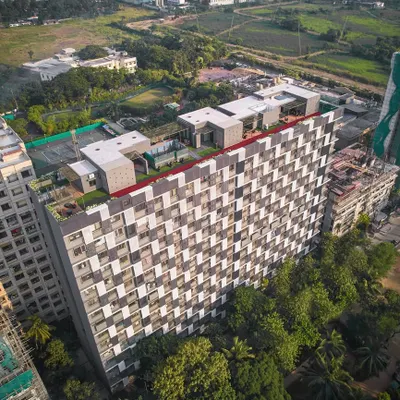 The DLH Mamta residential redevelopment project in Upper Juhu, Mumbai. The design features a striking zigzag facade of aluminum louvers, which adds a sense of movement and reduces the visual bulk of the structure while maximizing views over the adjacent green spaces.