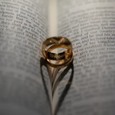 A creative and meaningful shot of the wedding rings. The shadow they cast on the pages of a bible forms a perfect heart, symbolizing a love blessed with faith.