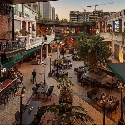 The full courtyard view of Street 1522 at dusk, where my landscape design, including the cobblestone paving, strategic planting, and ambient lighting, comes together to create a lively and immersive al fresco dining experience.