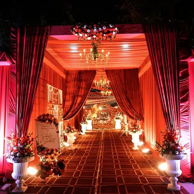 A grand entrance sets the tone for a spectacular wedding. I designed this luxurious entryway with rich red drapes, a crystal chandelier, and floral arrangements, creating a royal welcome for the guests.