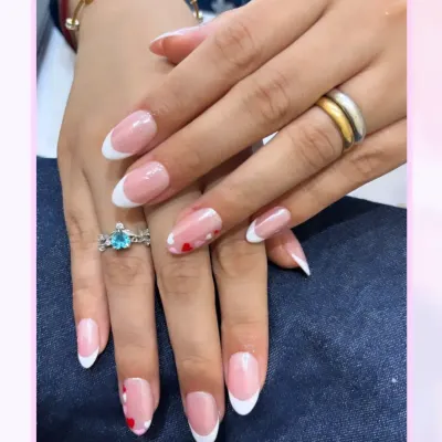 A perfect example of a modern French manicure. The clean, crisp white tips on these almond-shaped nails are complemented by tiny, hand-painted red hearts on the ring fingers.