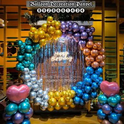 This birthday party setup features a full circular arch made of multi-colored chrome balloons. A central 'Happy Birthday' neon sign and shimmering fringe curtain create a perfect photo backdrop for celebrations in a restaurant or party hall.