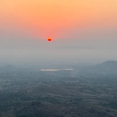 The beautiful orange sun rising over a misty landscape, as seen from the top of Minchukallu Betta. This is the view we wake up to.