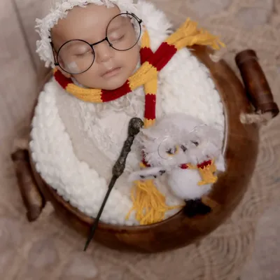 Welcome to the wizarding world, little one. This creative Harry Potter themed newborn shoot features a sleeping baby with iconic glasses, a Gryffindor scarf, and a magic wand, showing how we bring your favorite stories to life.