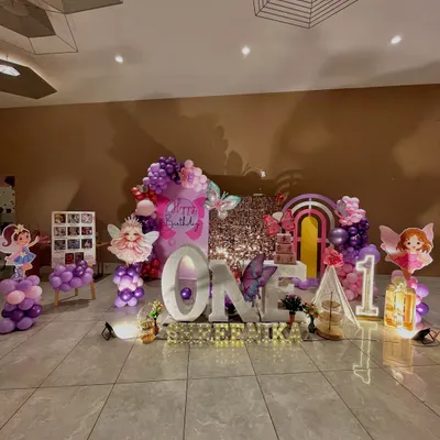 A full view of the enchanted butterfly and fairy theme for Shreenika's first birthday, featuring large 'ONE' letters, a sequin backdrop, and numerous character cutouts.