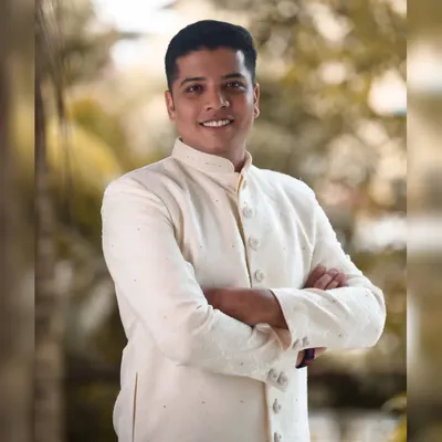 A classic groom portrait with a confident, relaxed pose and a warm smile. The soft, out-of-focus background ensures the groom is the sole focus of the image.