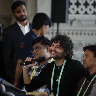 We capture audience participation and Q&A sessions effectively. This photo shows an attendee smiling as he asks a question, highlighting the interactive and engaging nature of the conference.