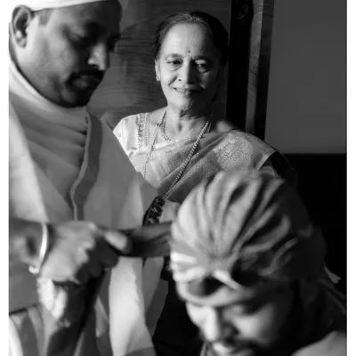 A touching black and white photo from a wedding ceremony, capturing the proud and loving expression of a mother watching the rituals. This image shows our ability to capture candid, emotional family moments during any event.