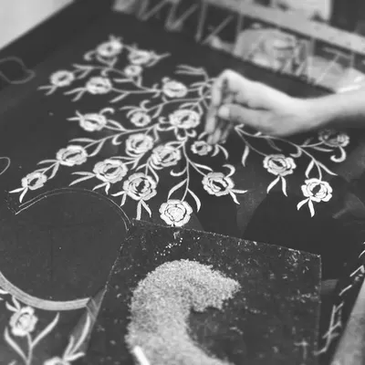 Here is a behind-the-scenes look at one of my skilled artisans at work. This image shows the process of hand-tracing a floral pattern onto fabric before the intricate embroidery begins.
