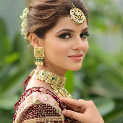 A classic bridal portrait. I created a soft glam look with defined eyes and a neutral lip color to complement her ornate jewelry and pastel lehenga. The hair is styled in an elegant bun adorned with fresh flowers.