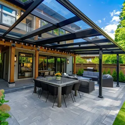 This expansive glass pergola creates a protected, all-season patio for dining and lounging. We engineered the sleek black frame and large glass panels to offer unobstructed views of the garden while ensuring complete shelter from rain and sun.