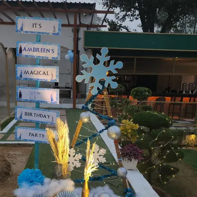 A creative directional sign for a Frozen-themed birthday party. The sign is styled to look like a snowy signpost from Arendelle, guiding guests to "Ambreen's Magical Birthday Party."