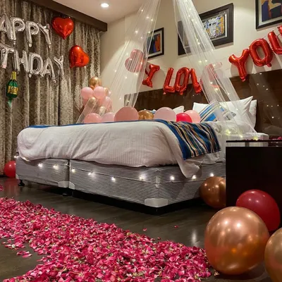 A complete romantic birthday surprise decoration. This room setup includes a bed canopy with fairy lights, a rose petal pathway, 'Happy Birthday' and 'I Love You' foil balloons, and a mix of regular and heart-shaped balloons.