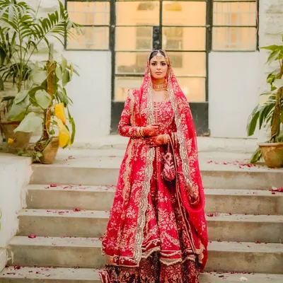 Here is a bride embodying pure grace and elegance on her Nikah day. Her magnificent red lehenga stands out against the timeless stone architecture, creating a portrait that is both regal and deeply personal. I believe in capturing the bride's individual story and presence in a way that feels majestic.