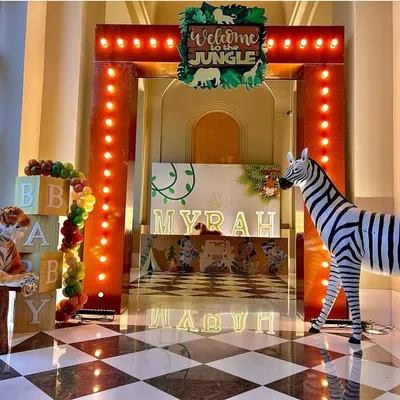 Welcome to the jungle! This grand entrance features a marquee-lit archway, life-sized zebra and tiger props, and a personalized light-up name display for "Myrah," creating an exciting start to the safari adventure.