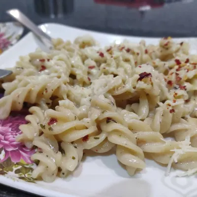 A delicious plate of fusilli pasta in a creamy white sauce, seasoned with herbs and chili flakes. A popular choice for all age groups.