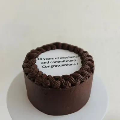 A chocolate bento cake for a corporate milestone, celebrating "18 years of excellence and commitment."