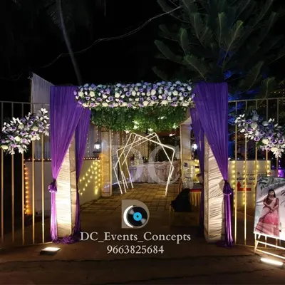 A beautiful entrance for a Roce ceremony, featuring purple drapes, white and purple floral arrangements, and a personalized welcome sign for the bride-to-be.