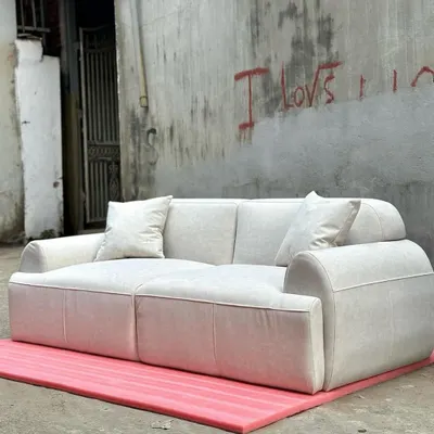 A modern, minimalist three-seater sofa with a blocky design and plush, off-white upholstery. This piece is perfect for a contemporary hotel lobby or a minimalist living space.
