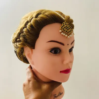 Here, we practice the placement of a maang tika with a side-parted, braided crown on a mannequin. Getting the position and angle right is key for a flattering bridal look.