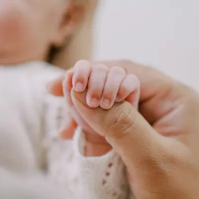 A newborn's hand wrapped around a parent's thumb. This simple, powerful image captures the instant connection and trust between a parent and child.