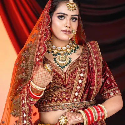 A deep maroon velvet lehenga that exudes royalty. The heavy embroidery on the blouse and skirt, paired with a grand Rajwadi necklace, creates a powerful and traditional bridal statement.