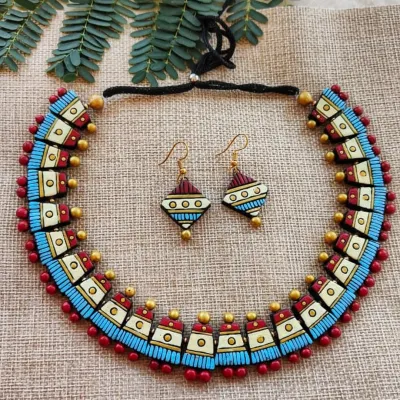 A unique choker-style necklace with geometric textured patterns in maroon, off-white, and sky blue. The matching hook earrings complete this modern, stylish set.