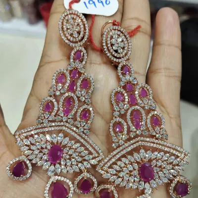These long, chandelier-style earrings are made with high-quality American diamonds and ruby-colored stones in a rose-gold finish. They are very glamorous and perfect for a cocktail party or reception.
