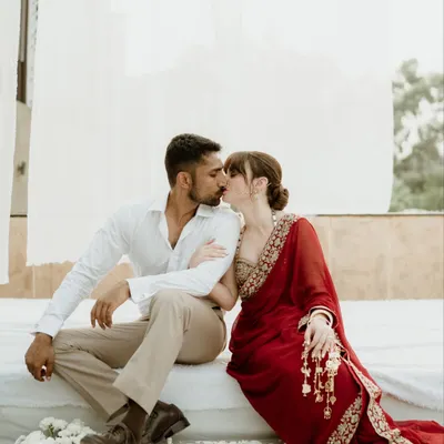 An intimate kiss shared between a couple in a serene, white-draped setting in Jammu. This tender moment captures the romance and stillness at the heart of their story.