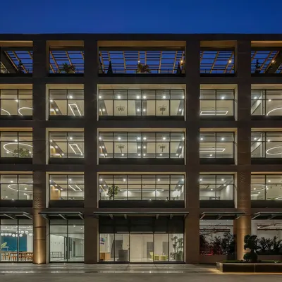 The facade of the Laurus Labs regional office in Vizag at dusk. The grid-like structure and large glass windows showcase the building's open and transparent design, which was engineered for natural cross-ventilation.
