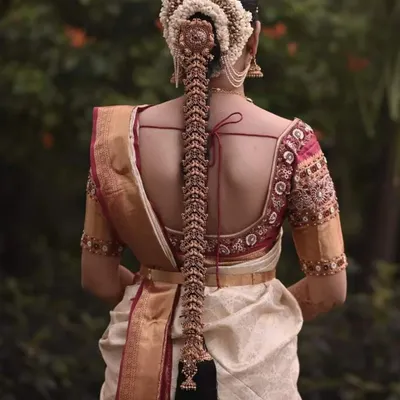 A stunning view of a bride's back, showcasing both her intricate hairstyle and our custom blouse. The blouse features a deep back with detailed embroidery along the borders, designed to be seen and admired.