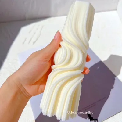 My wave twisted pillar candle, held to show its intricate and fluid design. It's a statement piece of decor, hand-poured from natural soy wax.