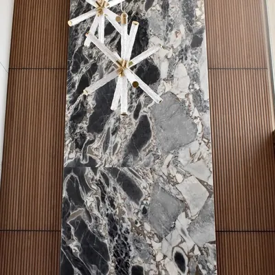 A powerful focal point for a high-ceilinged living room or lobby. We combined a large, bookmatched stone slab with textured wood panelling to create a feature wall that exudes modern luxury and artistic expression.