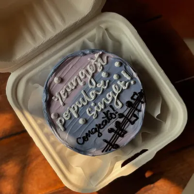 A congratulatory bento cake for a "young popular singer." The cake features a purple and blue ombre design with musical notes to celebrate a special achievement.