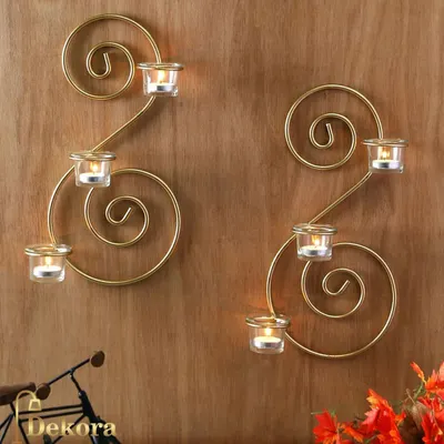 A set of two spiral-shaped wall sconces, designed to hold tea light candles. Their golden finish adds a warm, ambient glow to any room, perfect for creating a cozy atmosphere.