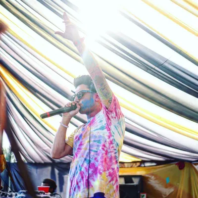 Hyping up the crowd during a daytime Holi party. My tie-dye shirt and the colors on my face show that I get fully into the spirit of the event.