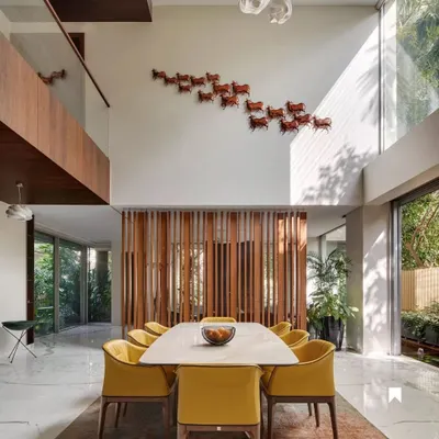 The double-height dining area in Kanasu, where natural light floods the space, highlighting the open-plan layout and connection to the upper floors.