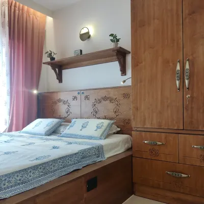 A beautiful master bedroom from the Sampada Home project, where a custom platform bed with a CNC-carved headboard is paired with a matching wardrobe. The design is unified by intricate floral motifs, creating a cohesive and elegant space.