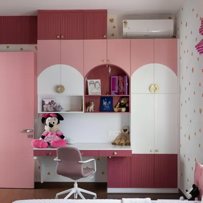 The completed kid's room from our Lakshya project. The design features custom cabinetry with an integrated desk and playful arched details, all in a charming pink and white palette with gold accents.