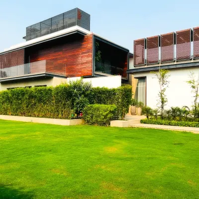 A view of a modern farmhouse in Sultanpur, Delhi. I used a clean, manicured lawn and tall, dense hedges to create a sense of privacy and frame the contemporary architecture of the home.