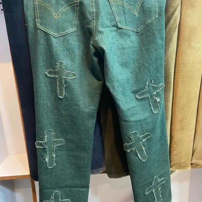 An example of bold customization. These green denim jeans feature custom-made, frayed-edge cross patches for a unique, standout look.