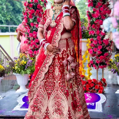 A vision in red. This stunning bride is ready for her forever, dressed in a traditional red lehenga with intricate gold embroidery, perfect for a classic wedding ceremony.